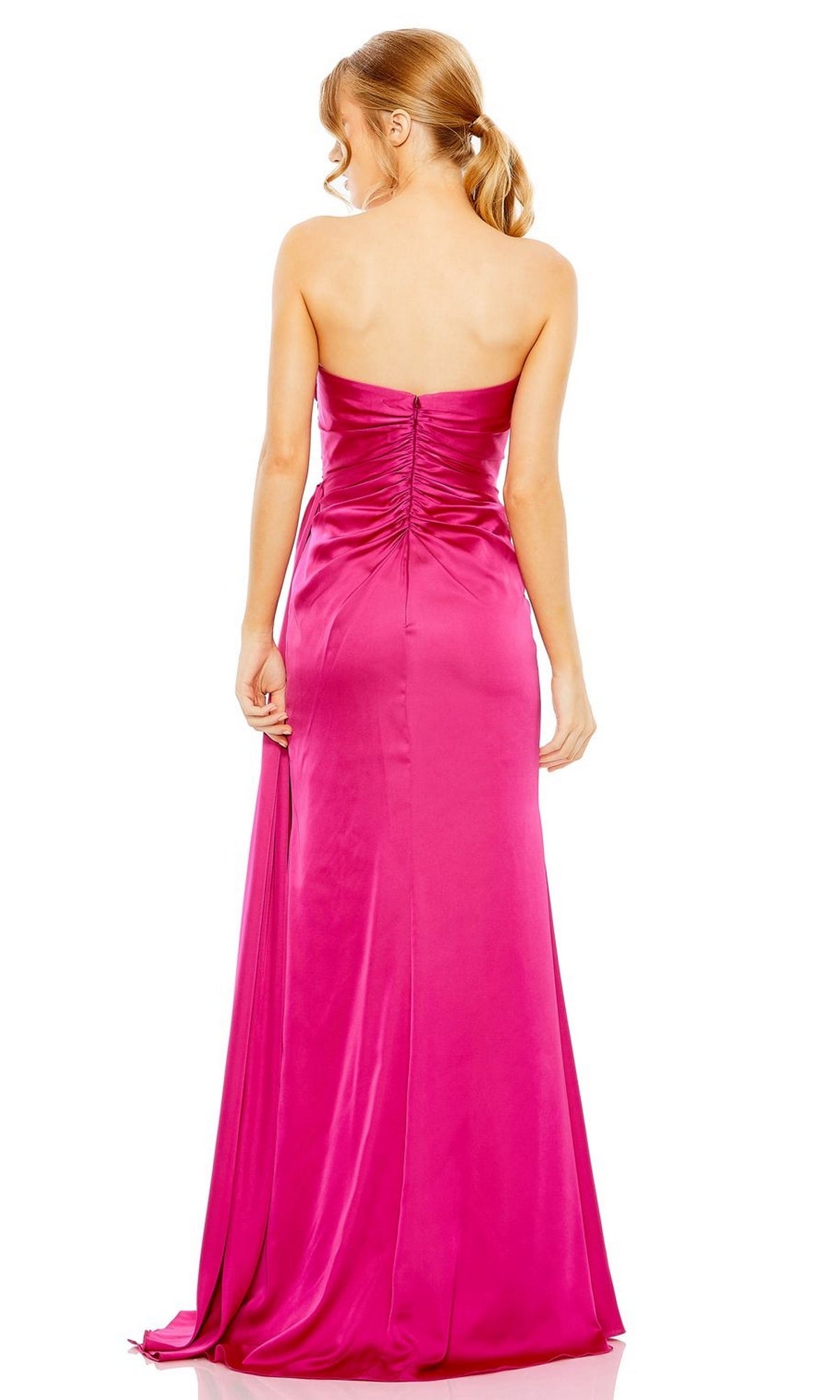 A woman with light brown hair in a ponytail is seen from behind against a white background, wearing the Mac Duggal 2211 Side-Drape Strapless Prom Gown in bright pink satin with a pleated bodice.